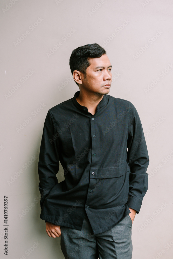 Obraz premium Thoughtful asian man in minimalist style clothing against neutral backdrop