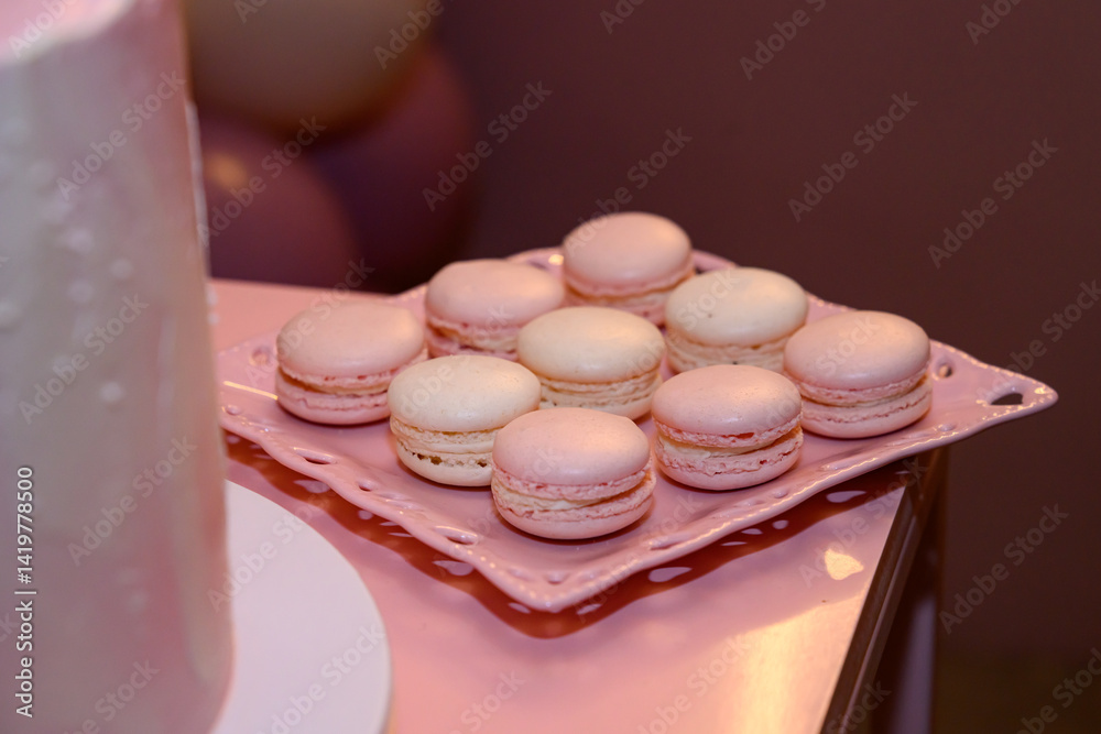 Delicate pink macarons with a creamy filling, arranged on a white cake stand.