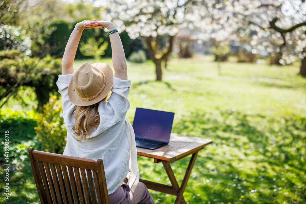 Relaxed woman stretching her arms while she working on laptop outdoors. Remote work concept