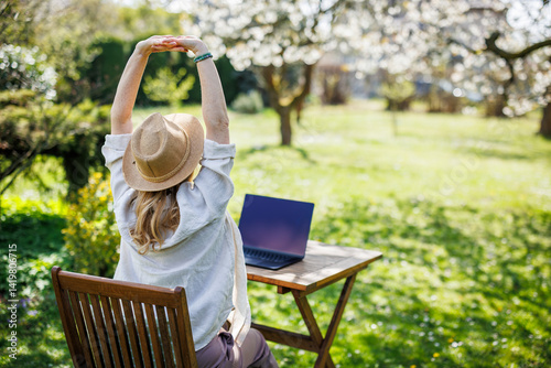 Obraz na płótnie Relaxed woman stretching her arms while she working on laptop outdoors. Remote work concept w salonie