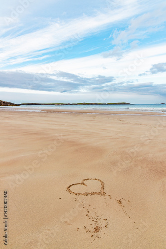 Fototapeta Naklejka Na Ścianę i Meble -  Ceannabeinne Beach shines under a clear summer sky. Crystal-clear waters, golden sand with a heart drawn on it, and lush green grass create a pristine and romantic coastal escape.

