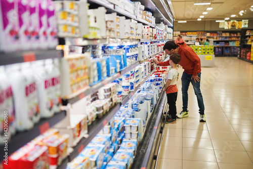 Father and son shopping in dairy section of supermarket