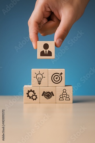 Stack of wooden blocks showing business icons being arranged in a pyramid. Concept of leadership, strategy, goal setting, teamwork, and organizational growth.