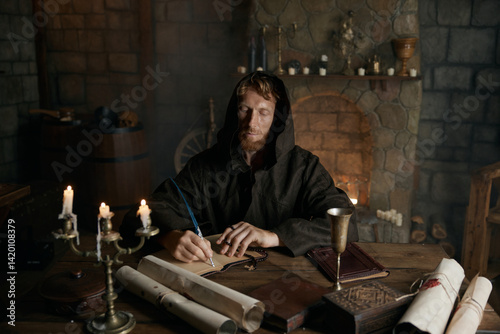 Photos Portrait of medieval monk writing historic manuscripts at table