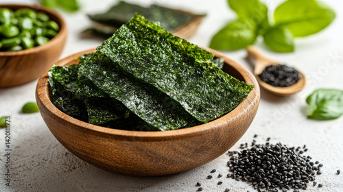 Flat lay of green nori seaweed flakes and powder in a wooden bowl and scoop, laid on a white tabletop