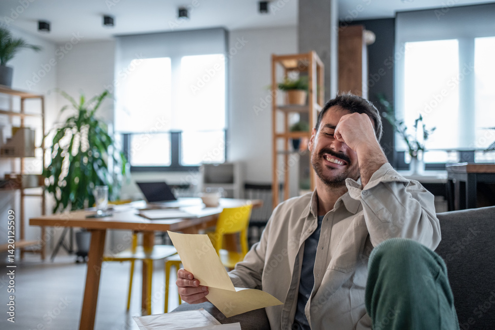 Fototapeta premium Man laughing while reading a letter in modern office