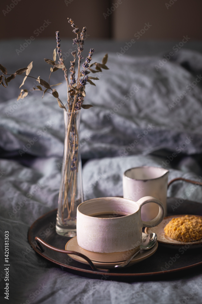 Morning coffee on vintage metal tray in bed with grey sheet and pillows.