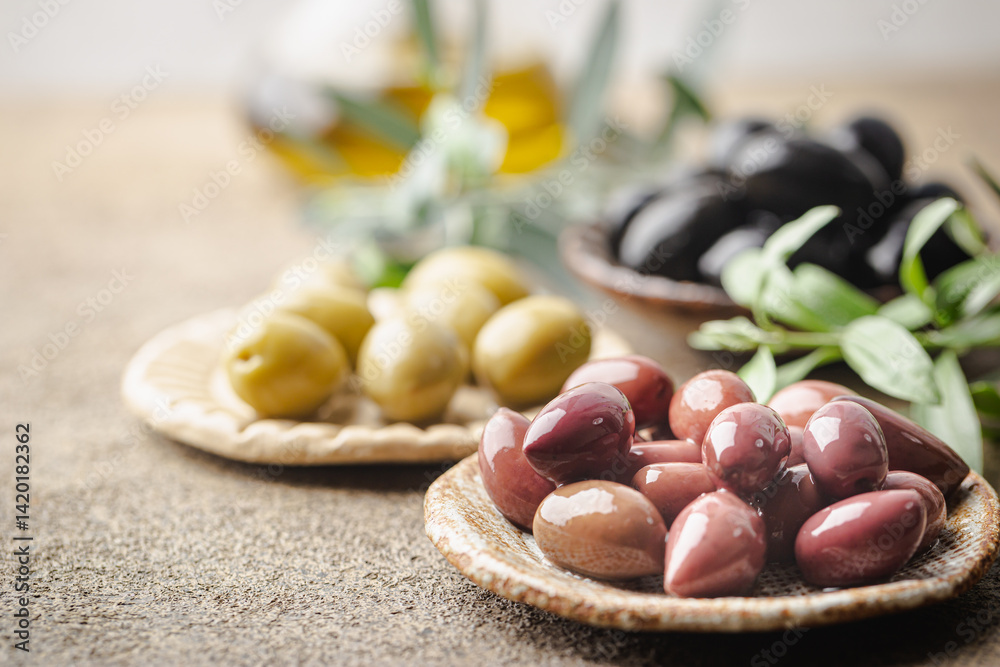 Variety of black and green olives and olive oil in bowls on stone background close up