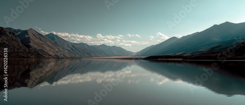 Serene landscape of mountains and a calm lake reflecting the sky, showcasing a tranquil natural scene.