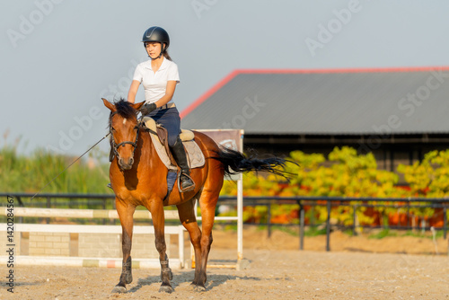 Smart teen girl enjoy to ride horse for exercise and train in the horse riding arena.