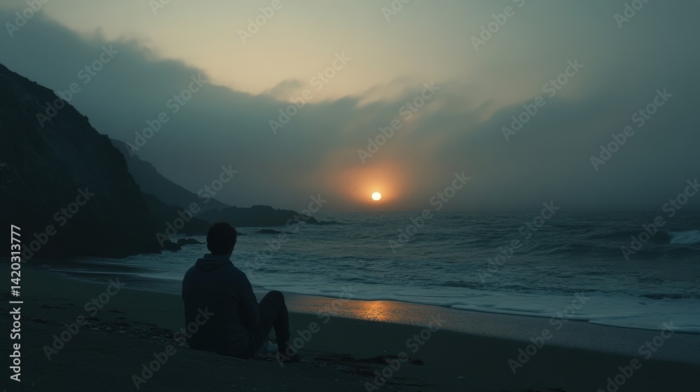 Fototapeta premium A solitary figure gazes at the sunset by the ocean, waves gently rolling in under a misty sky, capturing a moment of peace.