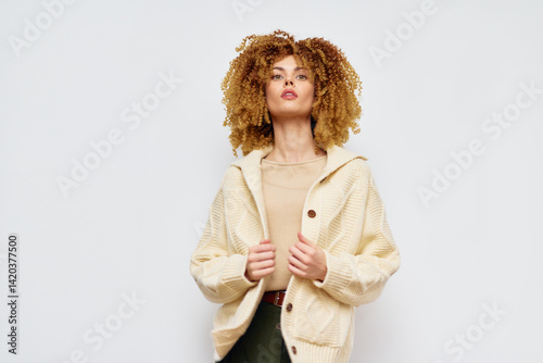 Obraz na płótnie Fashionable woman in a cozy cream colored sweater against a plain white background, showcasing modern style and confidence through her expression and attire w salonie
