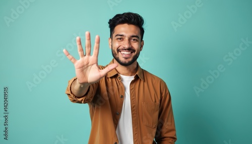 Young Hispanic man smiling. Handsome male showing number five with hand forward. Happy guy counts with fingers. Smiling face looking at camera. Joyful expression, counting down, showing five.