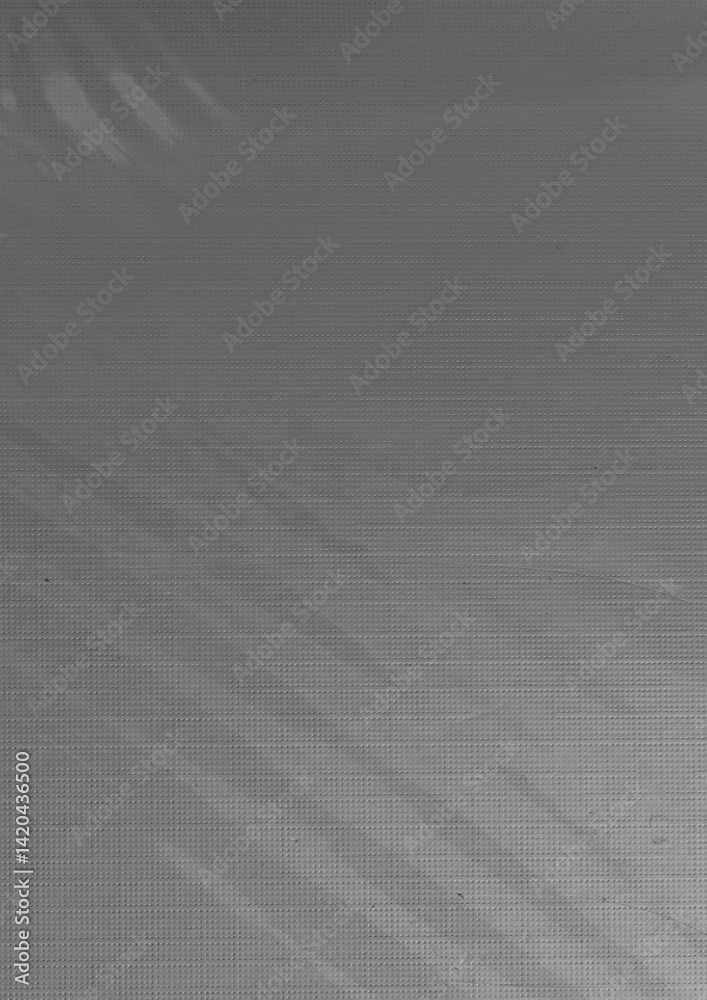 Fototapeta premium Minimal abstract texture featuring a soft light reflection across a slightly transparent, grid-patterned foil overlaying paper.