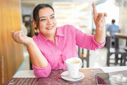 Schilderij op canvas Happy customer ordering in a coffee shop raising her finger and smiling