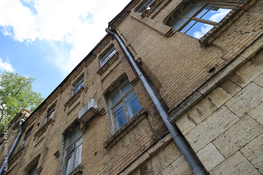 A View Of The Exterior Of A Brick Building With Several Windows And Metal Pipes. A View Of The Exterior Of A Brick Building With Several Windows And Metal Pipes.