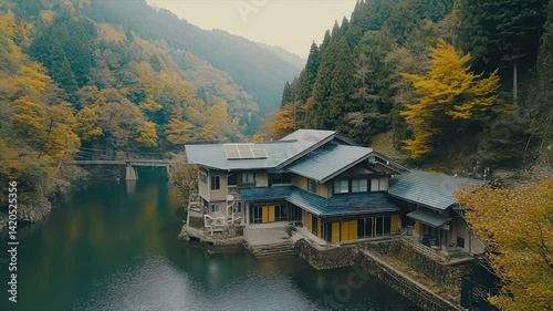 Autumnal mountain lodge by a serene lake.  A tranquil, wooden chalet nestled amongst autumn foliage, reflecting on the calm water of a mountain lake