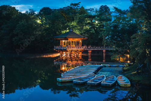 Obraz na płótnie Illuminated Ukimido Pavilion reflects on Nara Park's Sagi-ike Pond, with boats ready for visitors.. w salonie