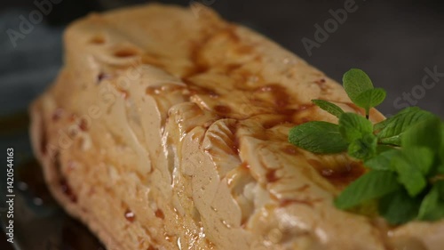 A tempting molotov pudding, its golden caramel glaze contrasting with the light meringue, beautifully garnished with fresh green mint leaves.