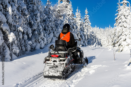 Snowmobile parked on a trail through the snowy forest on a beautiful winter day