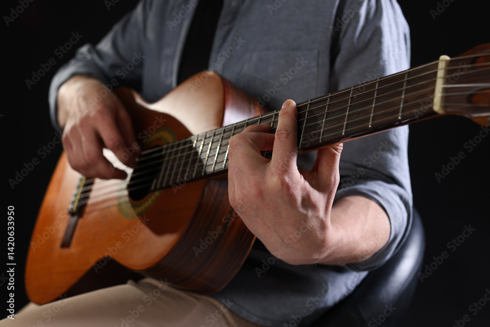 Man playing guitar on black background, focus on hand Man playing guitar on black background, focus on hand