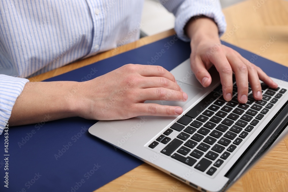 Man working on laptop at wooden desk in office, closeup Man working on laptop at wooden desk in office, closeup