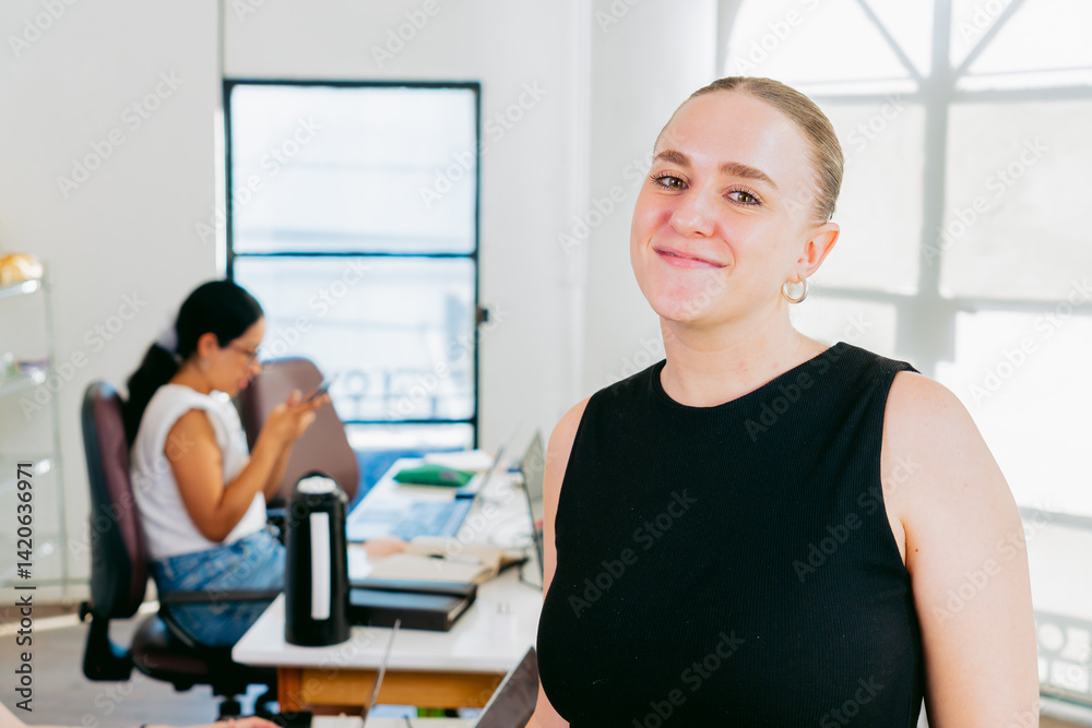 Fototapeta premium Young latina woman smiles looking at camera in a relaxed coworking space