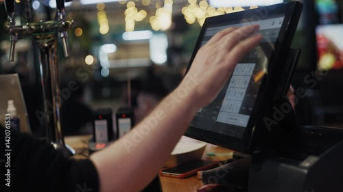 Close-up of hands operating a digital point-of-sale terminal in a fast food restaurant.