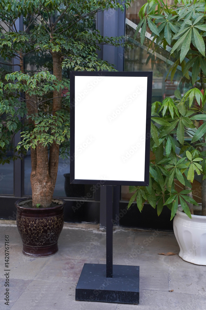 Blank white outdoor advertising stand or sandwich board mock up template. Clear street signage board placed by an outdoor dinning area of a restaurant. Background texture of standee on street.