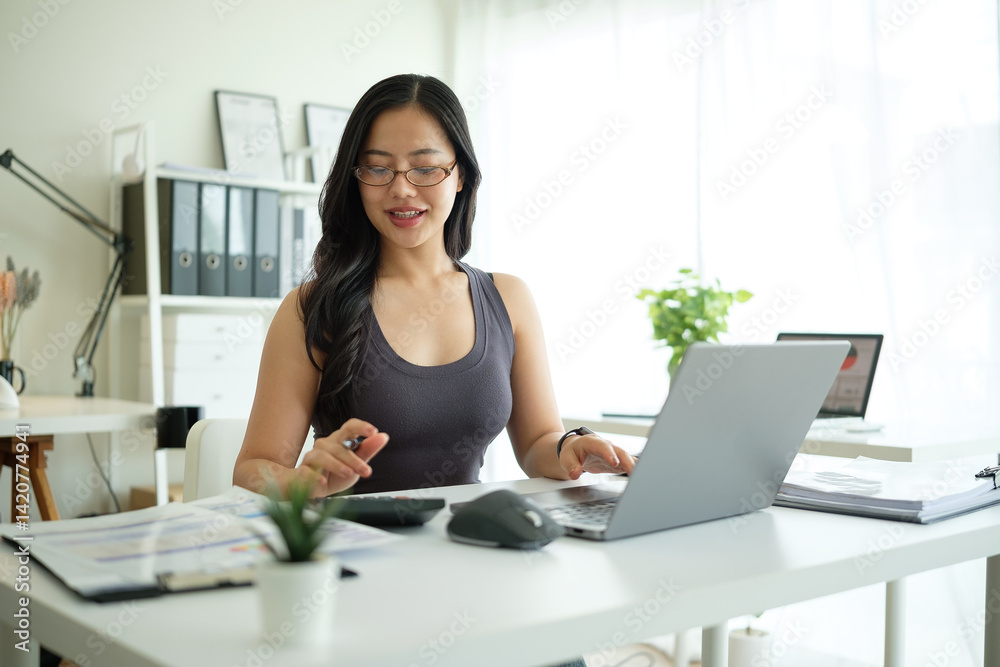 Young entrepreneur managing finances at office desk in a bright office. Young entrepreneur managing finances at office desk in a bright office.
