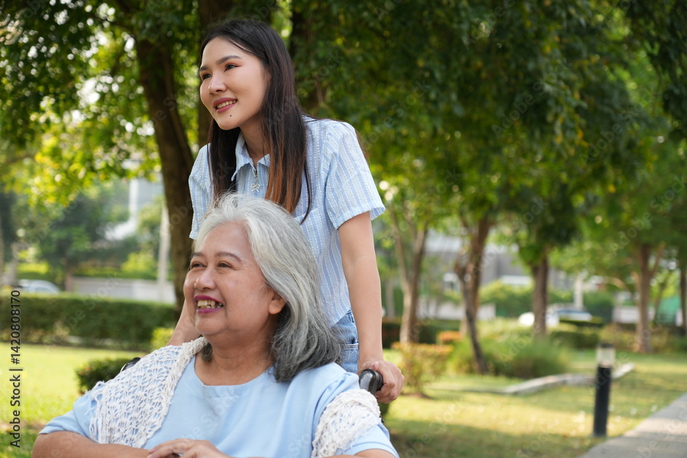 Two women, the daughter pushing a stroller with her elderly mother, walk in the garden and chat happily.