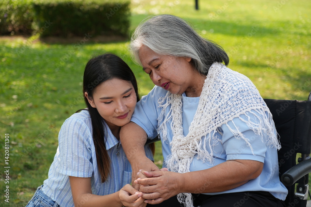 Two women, the daughter pushing a stroller with her elderly mother, walk in the garden and chat happily.