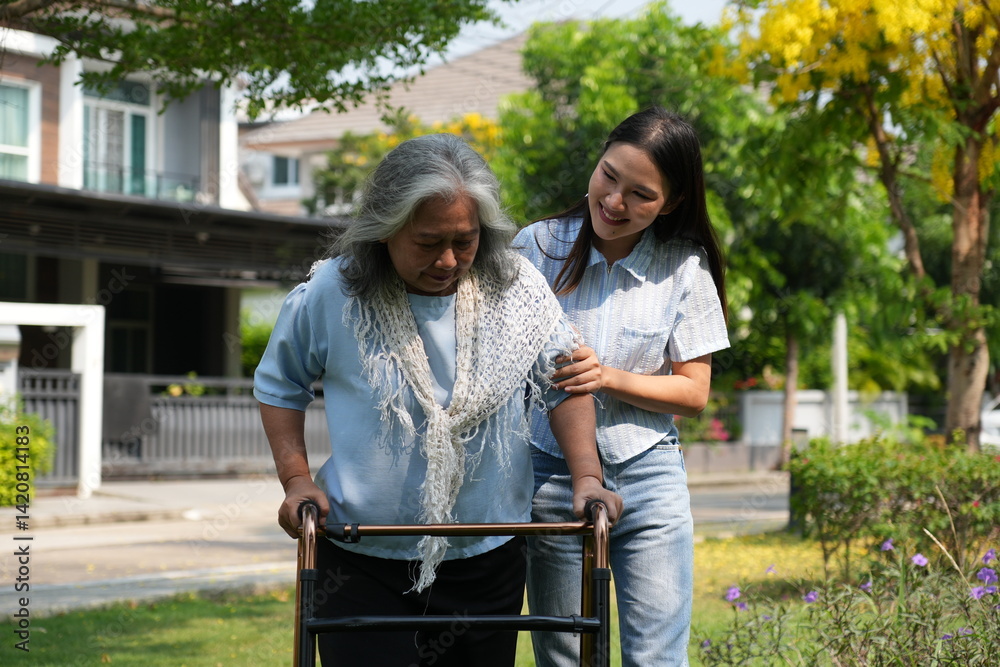 Two women, the daughter pushing a stroller with her elderly mother, walk in the garden and chat happily.