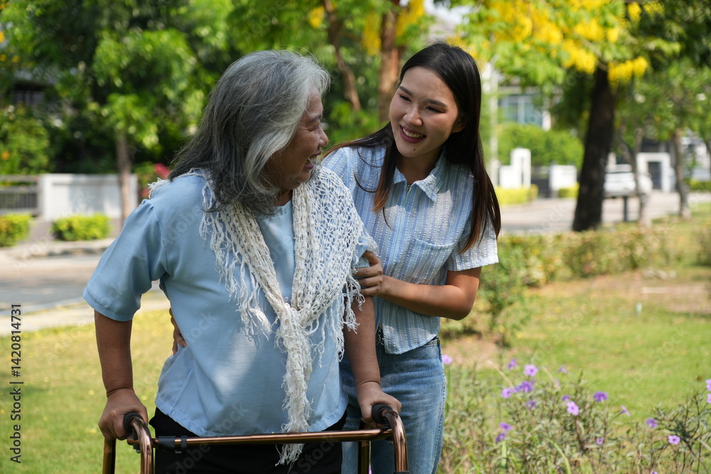 Two women, the daughter pushing a stroller with her elderly mother, walk in the garden and chat happily.