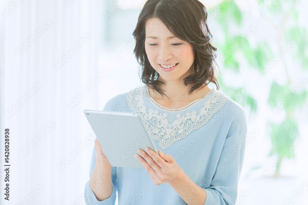 タブレットを操作する中年女性 タブレットを操作する中年女性