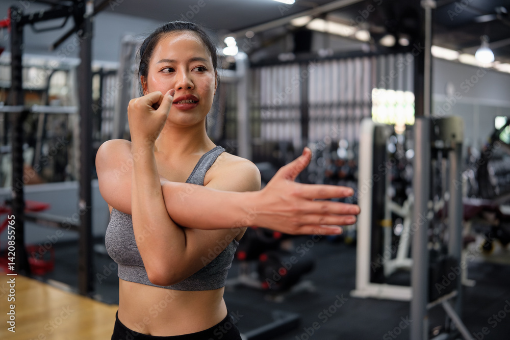 Fototapeta premium Smiling female athlete stretching before workout in a gym. Wellness, fitness and healthy lifestyles concept.