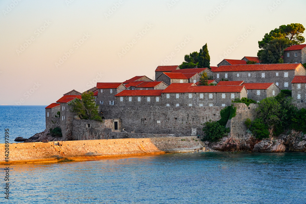 Houses of Sveti Stefan, a medieval village located on a small island connected to the mainland by a narrow tombolo (sandy isthmus) in the bay of Budva along the Adriatic Coast, Montenegro