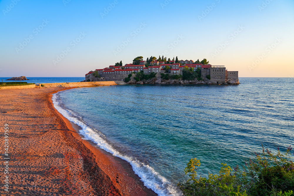 Beach of Sveti Stefan, a medieval village located on a small island connected to the mainland by a narrow tombolo (sandy isthmus) in the bay of Budva along the Adriatic Coast, Montenegro