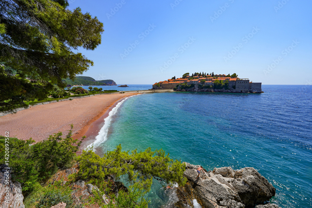 Beach of Sveti Stefan, a medieval village located on a small island connected to the mainland by a narrow tombolo (sandy isthmus) in the bay of Budva along the Adriatic Coast, Montenegro