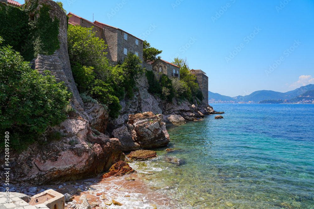 Fortification wall of Sveti Stefan, a medieval village located on a small island connected to the mainland by a narrow tombolo (sandy isthmus) in the bay of Budva along the Adriatic Coast, Montenegro