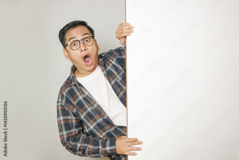 A man peeking behind wall seeing something with confused expression A man peeking behind wall seeing something with confused expression