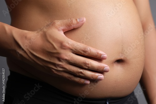 close up portrait of overweight obese man's hand holding his big belly