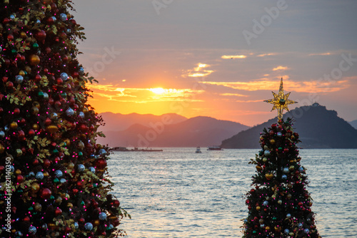 Obraz na płótnie Seaside Christmas Trees at Sunset with Mountain Silhouette w salonie