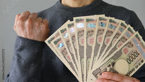 大量の一万円札を持ちポーズする人物