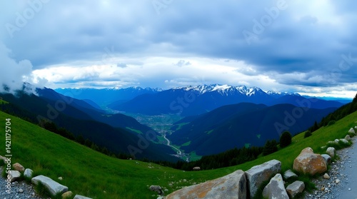 Majestic mountain panorama with green slopes and snow-capped peaks under a dramatic sky. Scenic landscape, ideal for travel and nature themes.