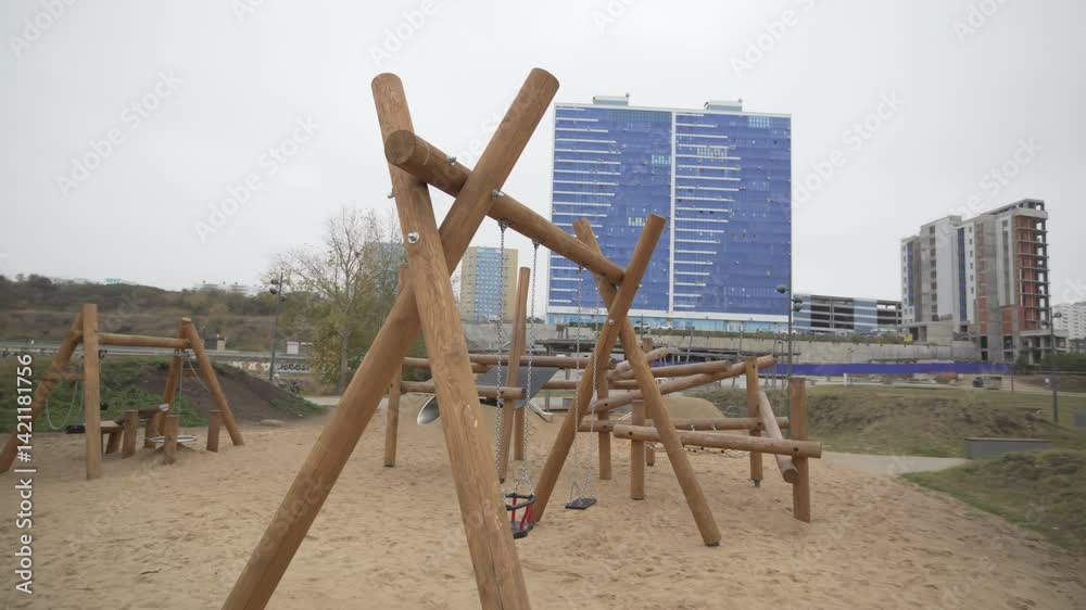 Wooden play structure stands on soft sand-covered playground. Design prioritizes child safety while encouraging physical activity and creative play Wooden play structure stands on soft sand-covered playground. Design prioritizes child safety while encouraging physical activity and creative play