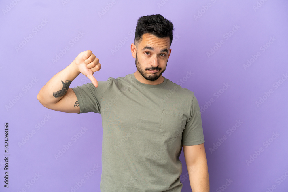Young caucasian man isolated on purple background showing thumb down with negative expression Young caucasian man isolated on purple background showing thumb down with negative expression