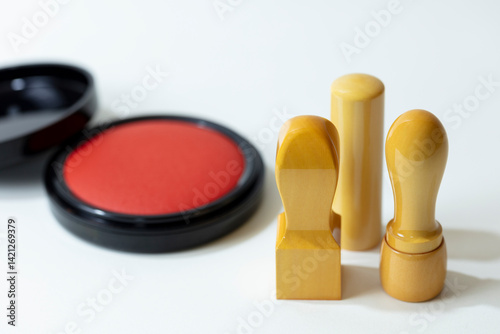 There are three seals and a plate of red ink pad on the white table