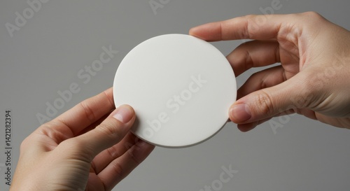 Hand Holding a White Circular Coaster