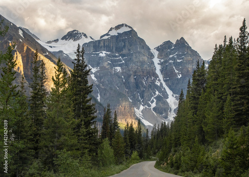 Fototapeta Naklejka Na Ścianę i Meble -  Majestic mountain landscape with winding road and lush forest at sunset in North America